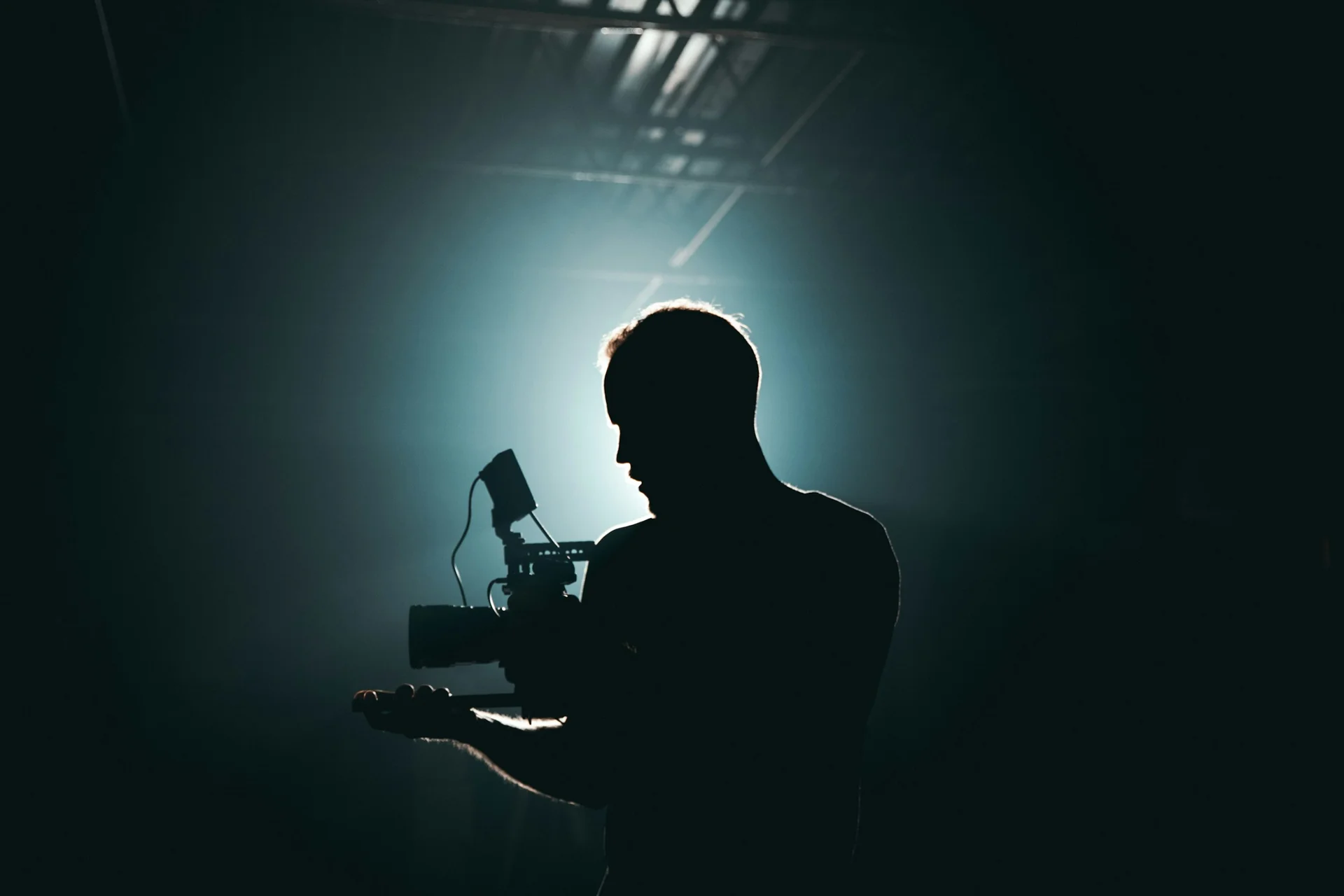 Camera operator silhouetted against production lighting
